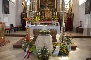Kirchenraum mit Altar, davor Blumenschmuck mit Sonnenblumen