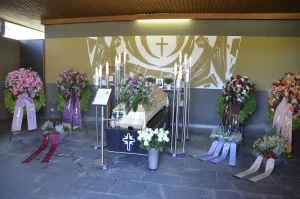 Aufbahrungshalle mit Sarg und mehreren Kränzen mit Schleifen